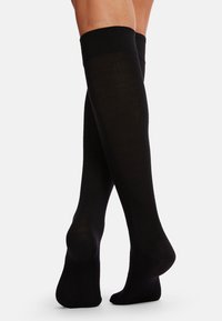 Knielange schwarze Socken aus glattem, dehnbarem Material mit geripptem Bündchen. Sie haben eine einheitliche Farbe und eine taillierte Form.