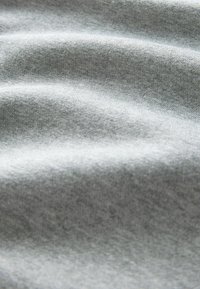 Szara tkanina o miękkiej fakturze, z delikatnymi falami i gładkim wykończeniem, wykonana z bawełny lub podobnego materiału, ukazująca równomierne rozłożenie koloru.