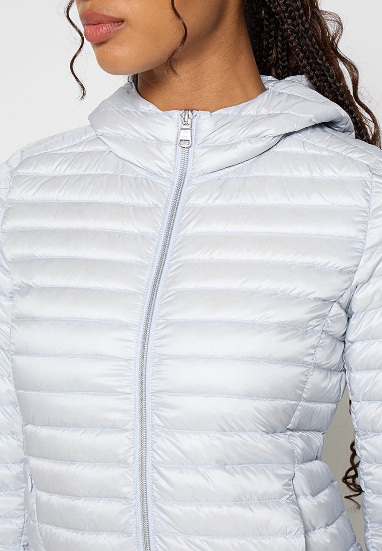 Giacca a vento azzurro chiaro con chiusura a zip, cappuccio e motivo a righe orizzontali. Texture liscia con dettaglio della cerniera riflettente.