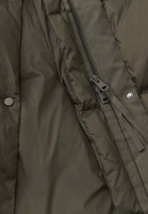 Intérieur d'une veste olive verte rembourrée avec texture matelassée, fermeture éclair visible et panneau en tissu, dotée de boutons-pression et d'un cordon de serrage.