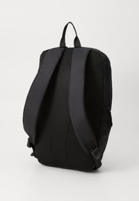 Zaino nero con spallacci imbottiti in rete e maniglia superiore. Il design include una tasca laterale con zip e una texture di tessuto liscia.