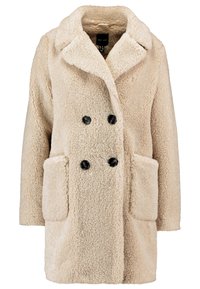 Abrigo beige de doble botonadura hecho de tela sherpa texturizada, con botones negros y dos bolsillos frontales. Diseño de longitud media con cuello con muesca.