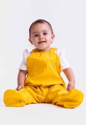 Yellow waterproof overalls with adjustable straps and smooth texture, worn over a white shirt, with a soft, round shape and no patterns.