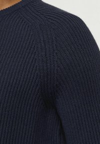 Maglione a coste blu navy con collo rotondo e motivo testurizzato, che mette in risalto una vestibilità aderente nella zona delle spalle.