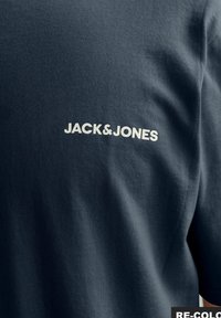 T-shirt en coton bleu foncé avec des manches courtes et un col rond, avec un logo "JACK&JONES" imprimé en blanc au dos.