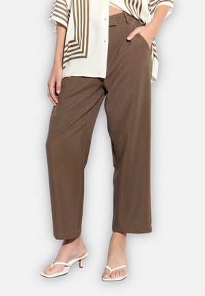 Bruine wijde broekspijpen gemaakt van een getextureerde stof. Heeft een rechte snit, zijzakken en een hoge taille. Gecombineerd met witte sandalen met hak.