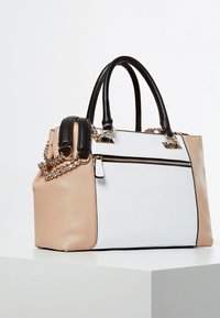 Sac à main au design structuré, en simili cuir noir, blanc et beige. Comprend un accent chaîne et une poche avant zippée.