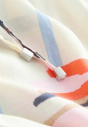 Kerge kangas mitmevärviliste abstraktsete mustritega pehmetes pastelltoonides, mille nöörilõppudel on hõbedased ruudukujulised detailid.