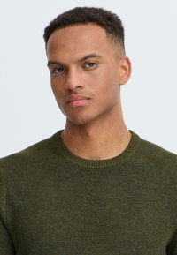 Groene gebreide trui met een ronde hals, met een gladde textuur en een slim fit ontwerp. Geen zichtbare patronen of versieringen.