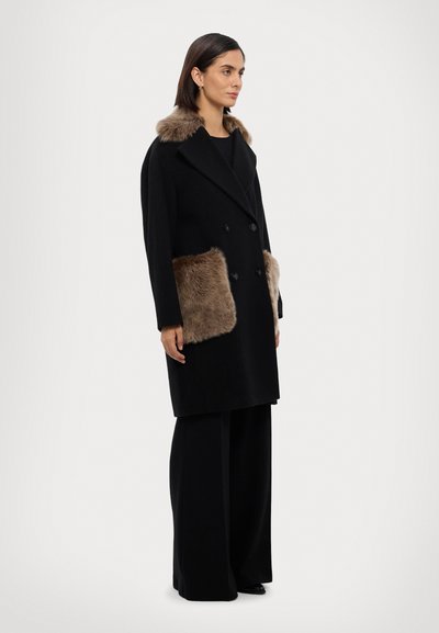 Cappotto di lana nero con design doppiopetto, dettagli in pelliccia sintetica sulle tasche e colletto foderato in pelliccia. Silhouette su misura, lunghezza al ginocchio.