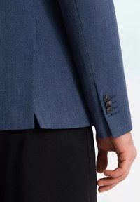 Granatowy żakiet w jodełkę o dopasowanym kroju, z trzema czarnymi guzikami na mankietach i rozcięciem z tyłu.