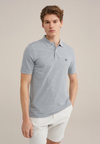 Gaiši pelēks polo krekls ar klasisku apkakli, īsām piedurknēm un izšūtu logotipu uz krūts, apvienots ar baltām šortiem.