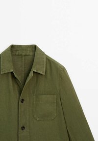 Chemise vert olive à manches longues avec col, boutons devant et une poche poitrine à gauche, présentée sur fond blanc.