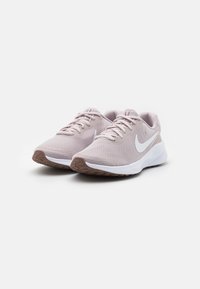 Baskets de sport rose clair avec une tige en maille texturée, logo Swoosh Nike blanc et semelle en caoutchouc brun. Design à laçage avec un col rembourré.