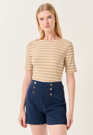 Beige geribbelde top met korte mouwen en witte strepen, gecombineerd met marineblauwe hoge taille shorts met gouden knoopaccenten.