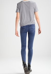 Randig kortärmad skjorta i grått och vitt, matchad med blå skinny jeans. Hög midja, texturerad tyg och svarta ankelstövlar med blixtlås.