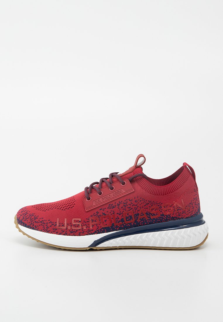 Chaussure de sport rouge avec une tige en mesh texturé, accents navy et semelle intermédiaire blanche. Présente des détails de logo sur le côté et un embout à motifs.
