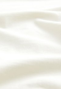 Fehér textília, puha tapintással, finom redők és sima felület jellemzi. Nincsenek minták vagy látható fémrészletek.