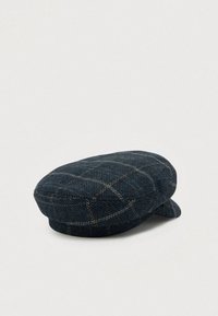 Tummansinisessä tasapohjaisessa myssyssä on vaaleanbeige ruutukuosi, jämäkkä kruunu ja lyhyt kaareva lippa, ja se on esillä vaaleaa taustaa vasten.