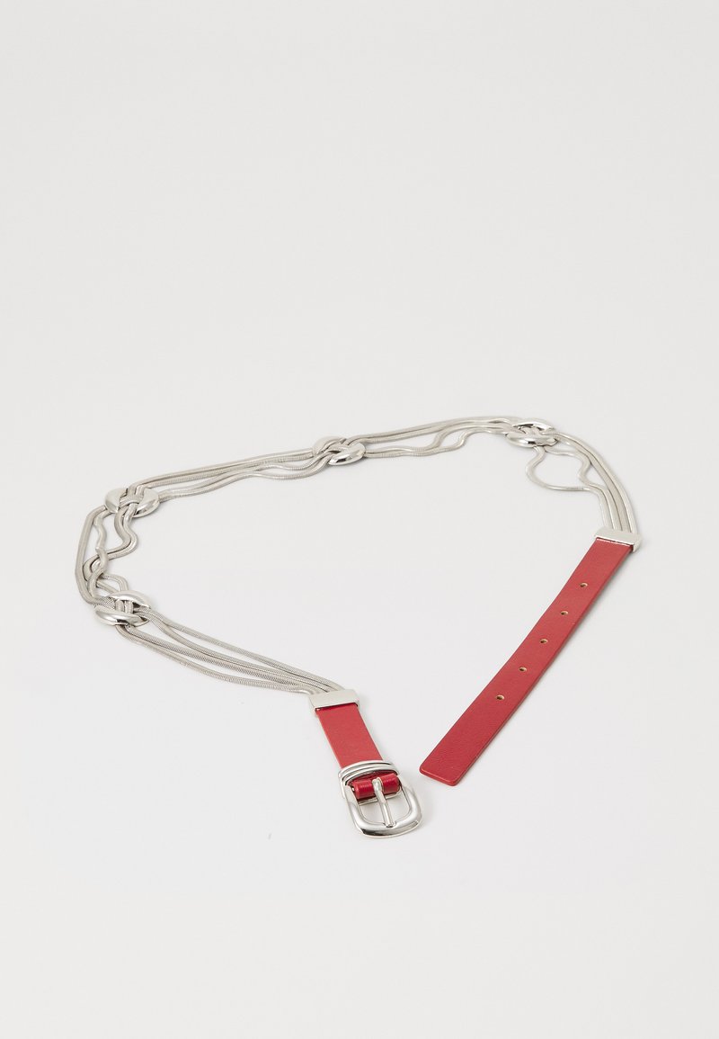 Rode leren riem met zilveren ketting schakels en een zilveren gesp, plat gelegd op een witte ondergrond.