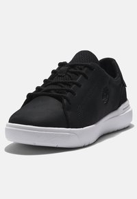 Black sneakers with a smooth upper, mesh details, lace-up design, white rubber sole, and subtle logo on the side.