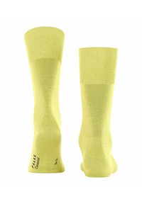 Gelbe knielange Socken mit gerippten Bündchen, aus einem glatten, leichten Stoff gefertigt. Auf einer Seite ist ein Logo aufgedruckt.