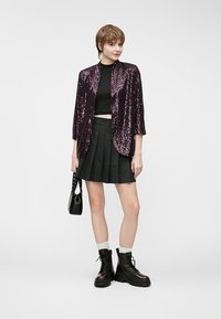 Säravlillate sädematerjaliga jakk musta lühikese toppi peal, koos musta pleediga seeliku ja tükkideks mustade saapatega. Must käekott kaasas.