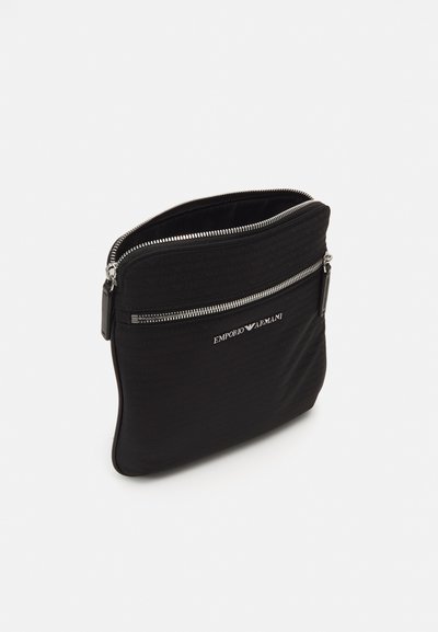 Black zippered pouch made of textured fabric. Features a logo and smooth silver hardware. Slim design with a rounded shape.