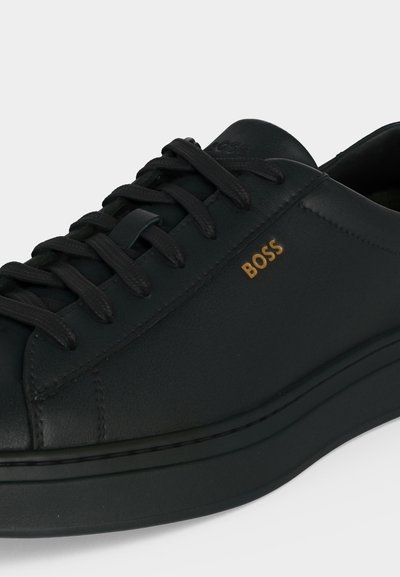 Baskets en cuir noir à lacets avec semelle épaisse, logo "BOSS" embossé en or sur le côté, couture soignée et col rembourré.