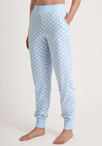 Lichtblauwe sweatpants met witte stippen, elastische tailleband, zijzakken en ribbelmanchetten bij de enkels. Zacht katoen materiaal.