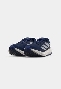 Marineblaue Sportschuhe mit einem atmungsaktiven Mesh-Obermaterial, weißen Akzenten und einer strukturierten Sohle. Mit drei weißen Streifen an der Seite.
