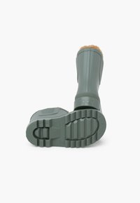 Stivale di gomma verde con design rigato, suola texture e fodera in pelliccia marrone sulla parte superiore. Presenta il logo del marchio sulla cinghia.