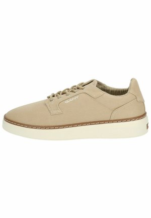 Zapatilla baja de lona beige con punta redonda, cierre de cordones, suela de goma marrón en contraste y un sutil detalle del logotipo en el costado.
