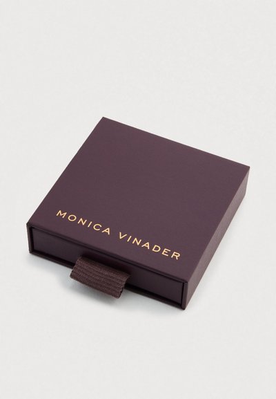 Nelikant, sügav lilla karp, matt viimistlus ja kuldsete tähtedega kiri "MONICA VINADER." Sisaldab tekstuurse kangast tõmbelinti.