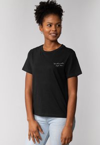 Zwarte kortemouwen t-shirt met ronde hals. Bevat witte tekst: "Ik wil niets zeggen, maar..." op de linkerkant van de borst.