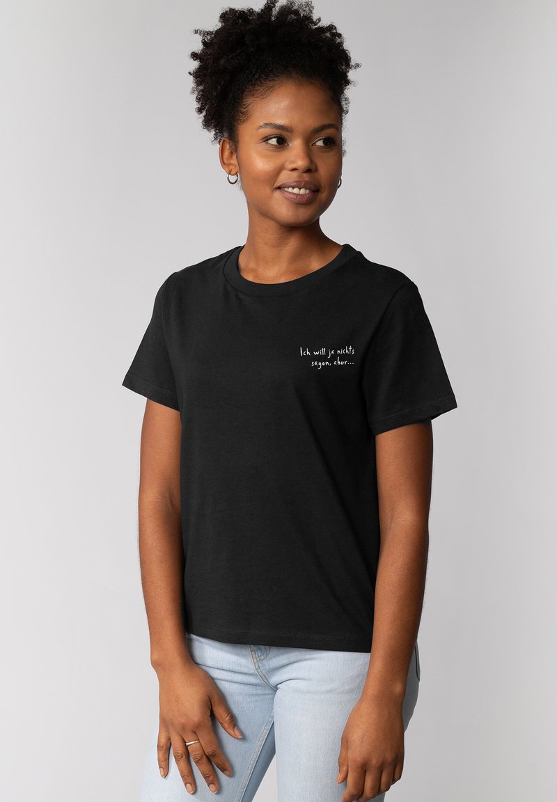 Zwarte kortemouwen t-shirt met ronde hals. Bevat witte tekst: "Ik wil niets zeggen, maar..." op de linkerkant van de borst.