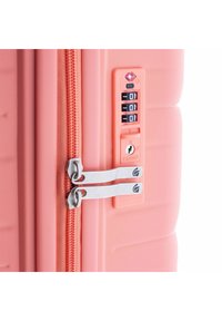 Valise rigide corail, dotée d'une serrure à combinaison approuvée par la TSA, de doubles fermetures éclair et d'une surface à texture lisse.