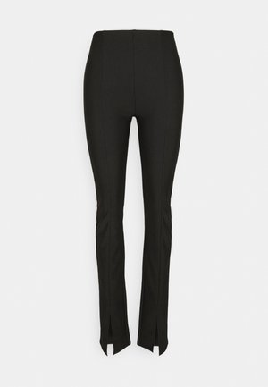 Pantalon noir ajusté en matière extensible, avec détails de coutures sur le devant et fentes latérales à l'ourlet. Texture lisse, design élégant.