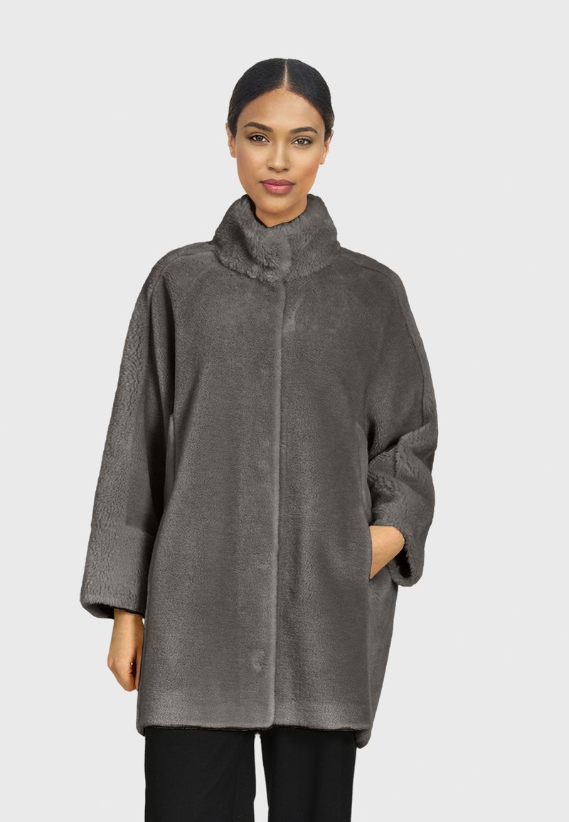 Sivi kaput od umjetnog krzna s visokim ovratnikom, oversized krojem i bočnim džepovima. Mekani materijal i besprijekoran dizajn povećavaju toplinu i udobnost.