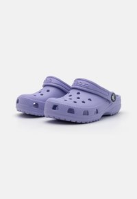 Tamancos Crocs roxos feitos de material sintético leve; apresentam orifícios de ventilação, uma alça traseira e uma sola texturizada para melhor aderência.