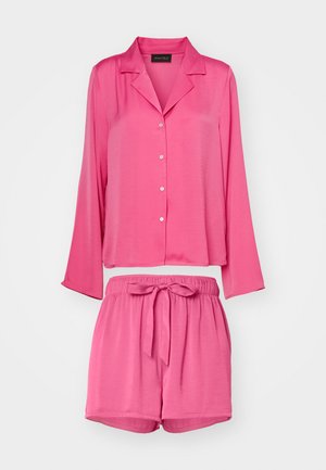 Conjunto de pijama de duas peças em rosa, apresentando uma blusa de botões de manga longa e calções com cintura elástica, decorados com um laço. Textura suave.