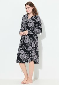 Mustat viitta, jossa on valkoinen paisley-kuvio, pitkät hihat, V-pääntie ja vyötäröllä solmittava vyö. Sileä kangas ja löysä istuvuus.