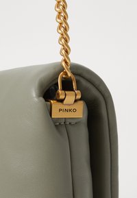 Olijfgroene leren handtas met een gouden kettinghengsel en sluiting. Bevat een geperst logo-plaat en een gladde textuur met subtiele stiksels.