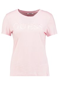 Camiseta de algodón rosa claro con cuello redondo, mangas cortas y un logo brillante de "GUESS" en un tono de rosa ligeramente más oscuro en la parte frontal.