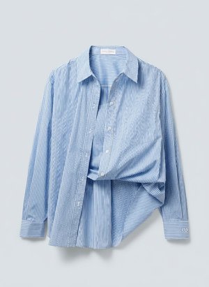 Πουκάμισο με κάθετες ρίγες σε ανοιχτό μπλε και λευκό χρώμα, με κουμπιά, μακρυά μανίκια και γιακά τύπου spread, εμφανίζεται κρεμασμένο με τη μία πλευρά διπλωμένη.