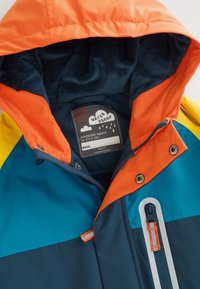 Waterdichte jas met een kleurrijk ontwerp, voorzien van een oranje capuchon en panelen in blauw, teal en geel. Zachte binnenvoering en een zak met ritssluiting.