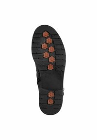 Black rubber sole featuring a textured pattern and brown hexagonal accents for grip. Visible tread grooves for enhanced traction.