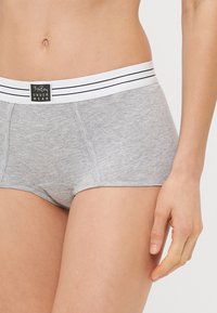 Γκρι βαμβακερά σλιπ μποξέρ με λευκή ελαστική ζώνη που έχει δύο μαύρες ρίγες. Λείος υφάσματος, με άνετη εφαρμογή και ραφές λεπτομερειών.