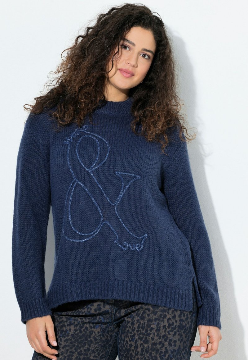 Maglione blu navy a maglia con scollo rotondo, caratterizzato da un grande design ampersand ricamato in blu. Polsini e orlo a costine, spacco laterale sul fondo.