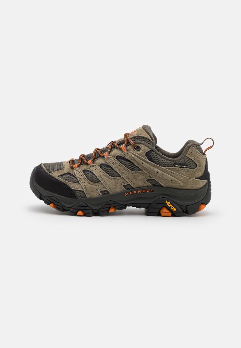 Chaussures de randonnée Merrell avec une tige en suede beige et en mesh, un capuchon de protection en caoutchouc noir, des accents orange, et une semelle Vibram durable. Design mi-haut.